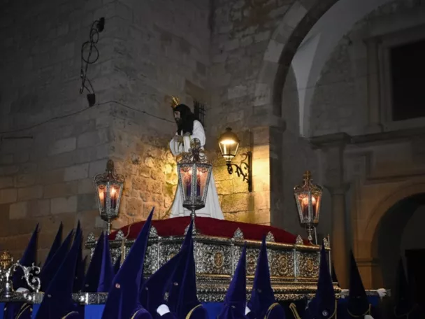 Paso religioso nocturno con nazarenos de túnica azul.