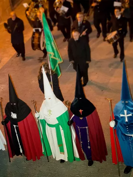 Nazarenos con túnicas de colores en procesión nocturna