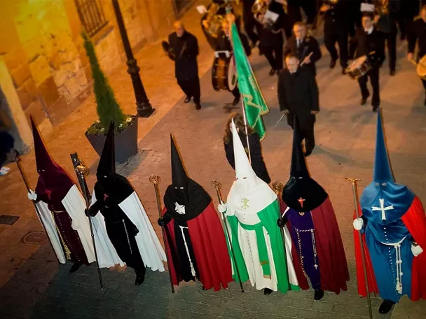 Nazarenos con túnicas de colores en procesión nocturna
