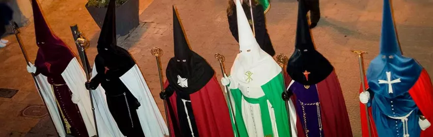 Nazarenos con túnicas de colores en procesión nocturna