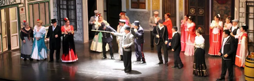 Escena teatral con elenco vestido de época sobre el escenario