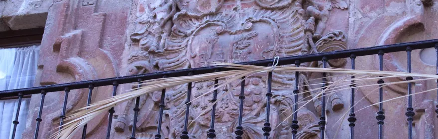 Escudo heráldico tallado en piedra sobre balcón de hierro.