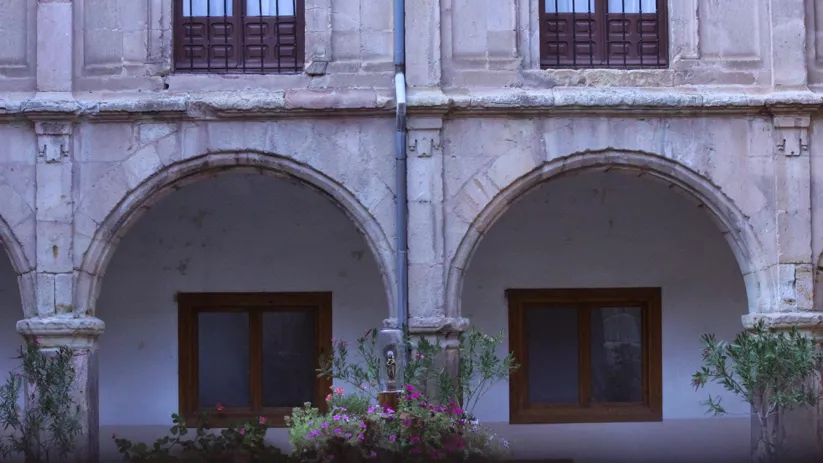 Patio interior con arcos de piedra y ventanas de madera.