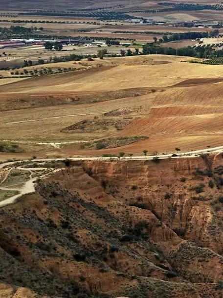 Vista aérea de cortados arcillosos junto a un embalse rodeado de campos agrícolas.
