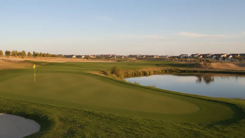 Green amplio con bandera junto al agua