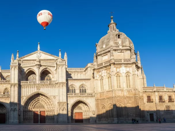 Globo aerostático sobrevolando una catedral monumental en una plaza amplia.