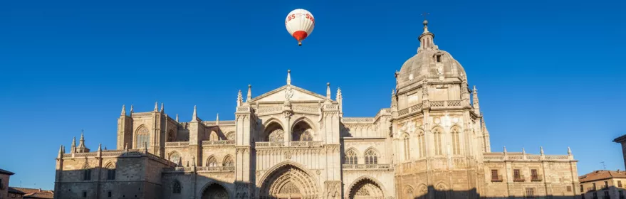 Globo aerostático sobrevolando una catedral monumental en una plaza amplia.