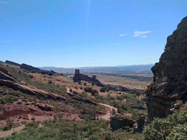 Paisaje rocoso con castillo sobre valle abierto.