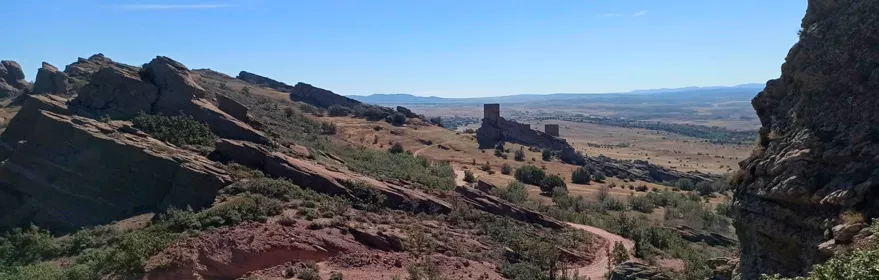 Paisaje rocoso con castillo sobre valle abierto.