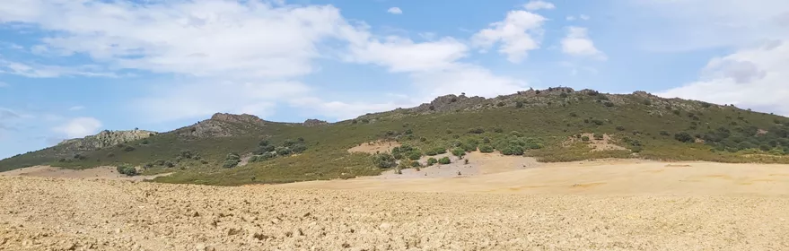 Paisaje de lomas verdes y campos secos bajo cielo azul