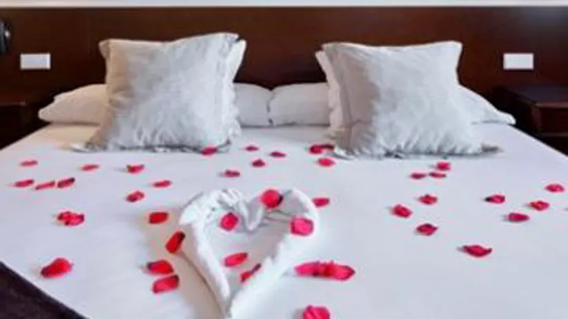 Imagen de una cama de un hotel con pétalos