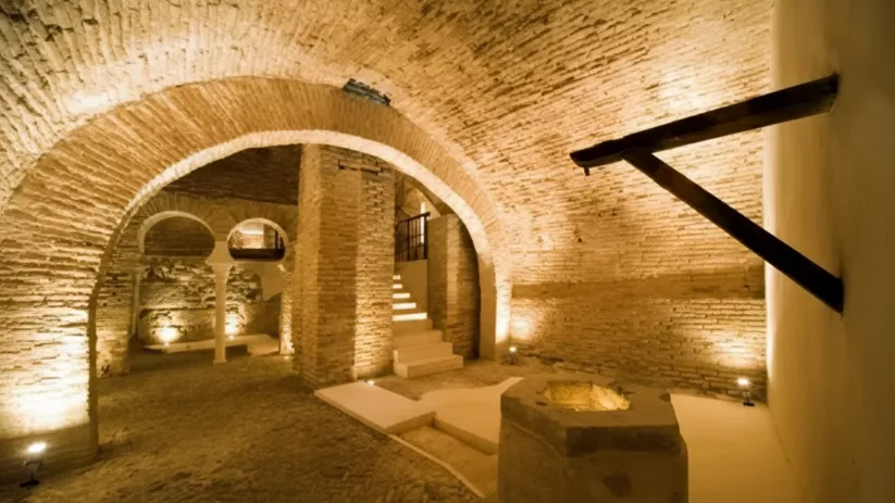 Detalle de arcos y columnas en sótano histórico con iluminación cálida ambiental.