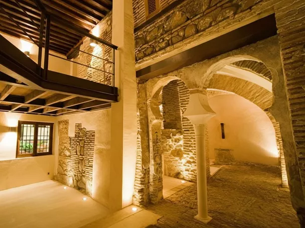 Estancia subterránea rehabilitada con vigas de madera, muros antiguos y suelo empedrado.