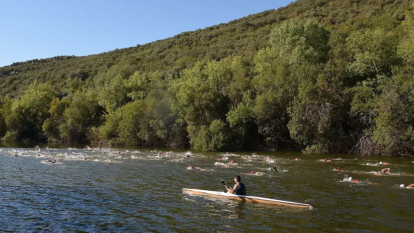 Nadadores en travesía fluvial con kayak de apoyo
