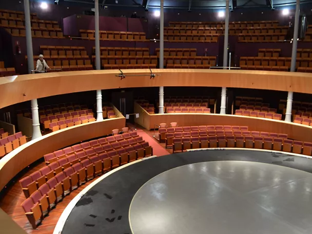 Vista panorámica de un teatro vacío con graderíos curvos y escenario central.