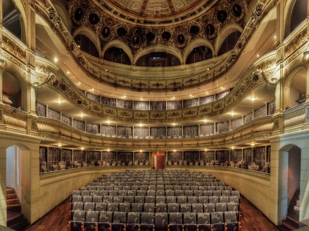 Sala de teatro con platea y varios pisos de palcos decorados.