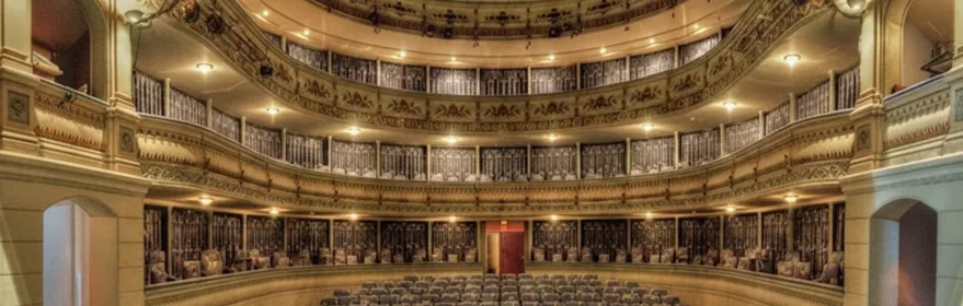 Sala de teatro con platea y varios pisos de palcos decorados.