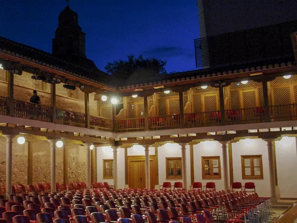 Patio interior con graderío y arquerías iluminadas de noche