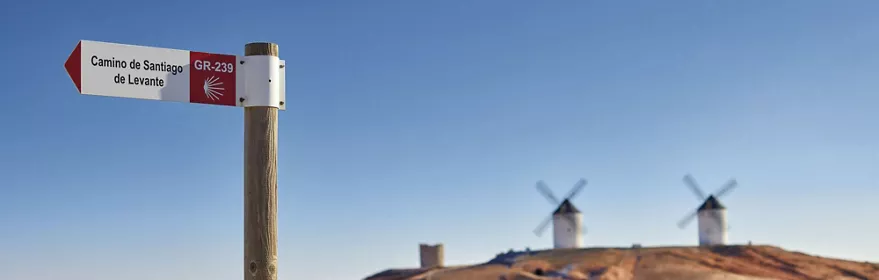 Señalización de ruta de peregrinación en camino rural entre campos de cultivo