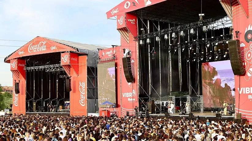 Multitud reunida frente a un gran escenario al aire libre durante un concierto.
