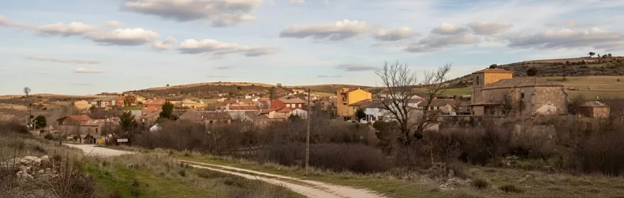 Vista general del pueblo en entorno rural con camino de acceso