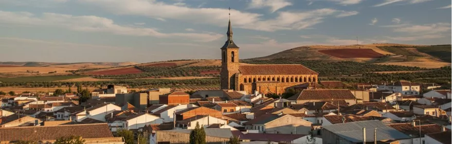 Vista panorámica de un casco urbano con iglesia y campos al fondo