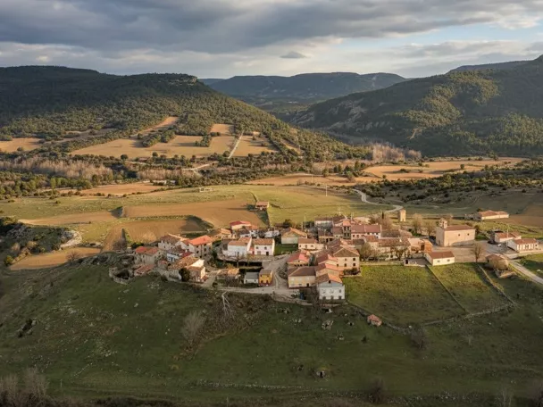 Vista aérea del pueblo rodeado de campos y montañas