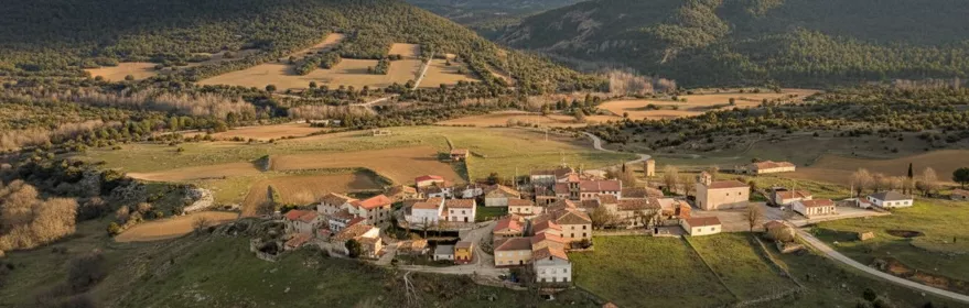 Vista aérea del pueblo rodeado de campos y montañas