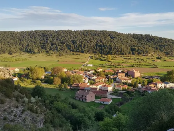 Vista aérea de un pequeño pueblo rodeado de campos y montes verdes