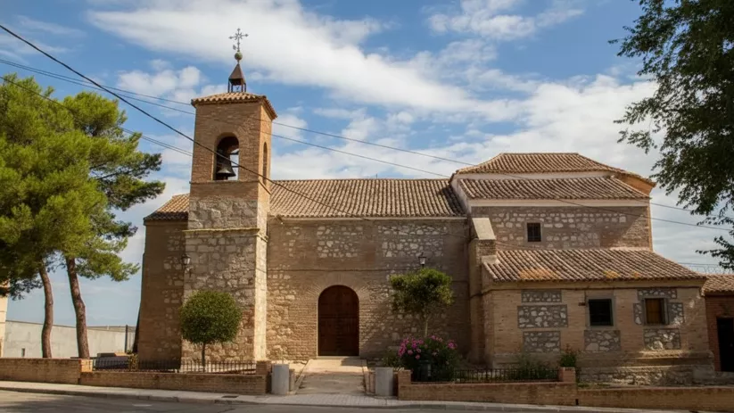 Fachada lateral de una ermita antigua construida en piedra y ladrillo, con una pequeña torre campanario y tejados de teja árabe.