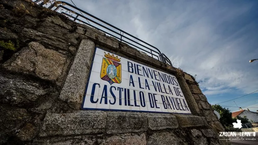Cartel de bienvenida de cerámica incrustado en un muro de piedra.