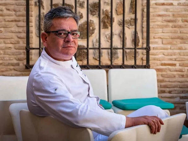 Cocinero sentado en una terraza interior con sillas blancas