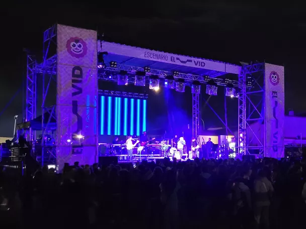 Escenario nocturno con concierto y público multitudinario