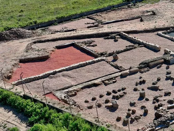 Vista aérea amplia de ruinas con estanque central y estructuras rectangulares.
