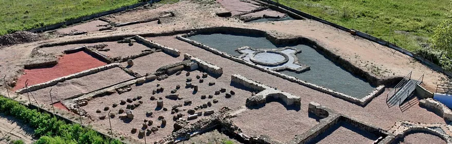 Vista aérea amplia de ruinas con estanque central y estructuras rectangulares.