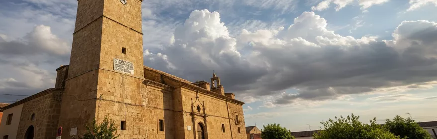 Iglesia de piedra con torre y cielo nuboso al atardecer