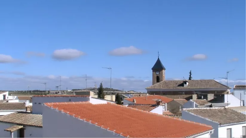 Una toma de nivel superior que muestra los tejados de un pueblo con el campanario de una iglesia a lo lejos.
