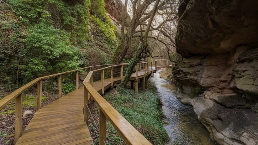 Pasarela de madera junto a arroyo entre paredes rocosas