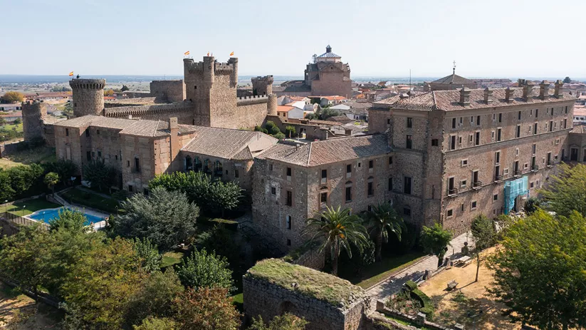Fortaleza de piedra con torres y edificios históricos adosados.