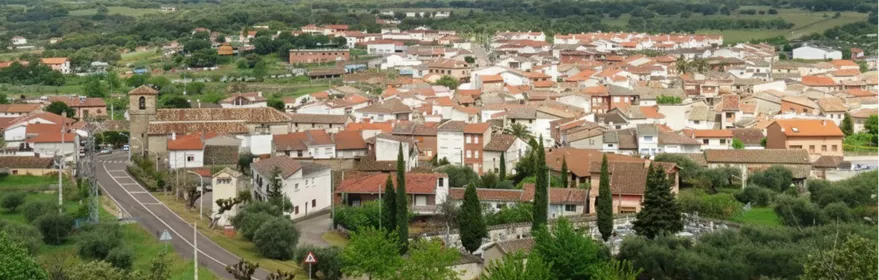 Vista panorámica de un pueblo rodeado de montañas y zonas verdes.