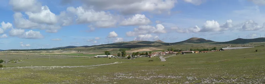 Panorámica de campos abiertos con colinas suaves y cielo con nubes dispersas.