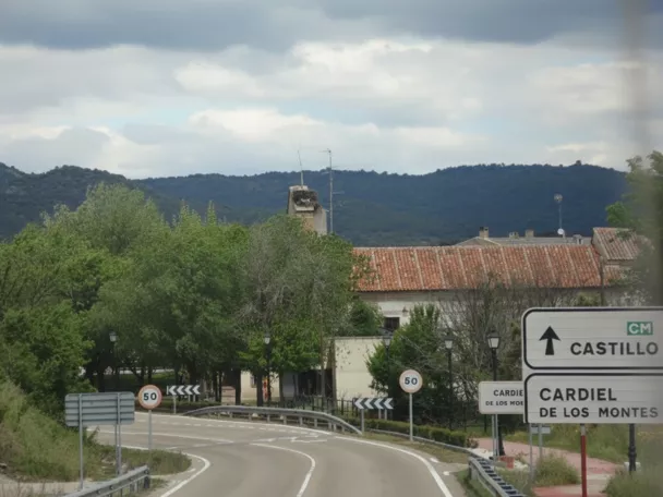 Carretera de acceso con señalización y montes al fondo