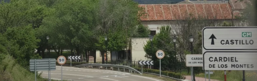 Carretera de acceso con señalización y montes al fondo