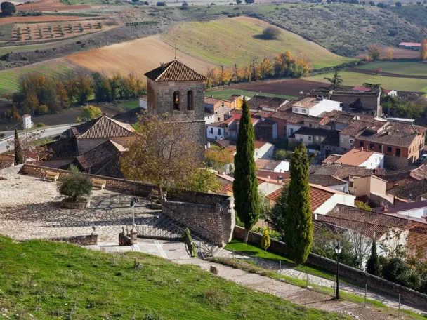 Vista elevada de pueblo con torre y campos de cultivo.