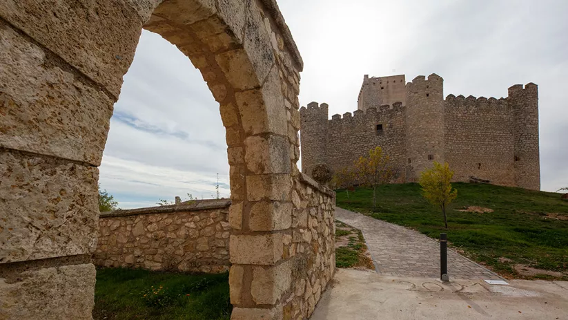 Murallas y torres de piedra junto a camino empedrado.