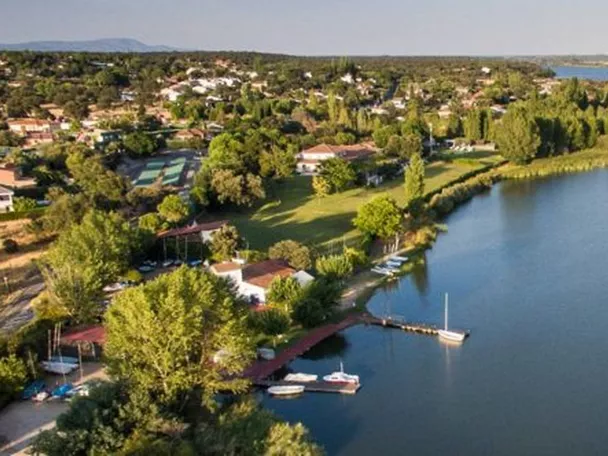 Vista aérea de un embalse con orilla arbolada, embarcaciones y zonas verdes