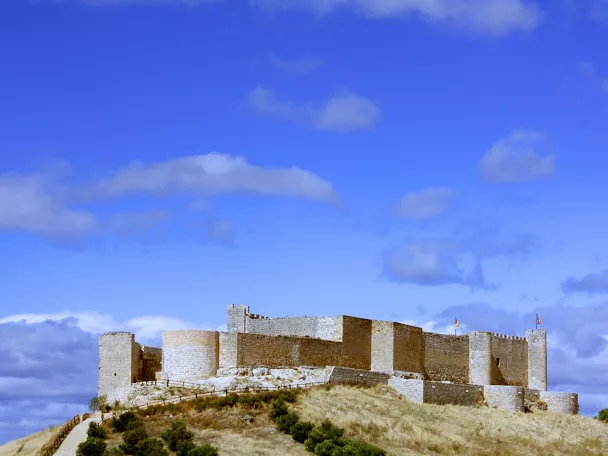 Castillo de piedra sobre colina bajo cielo azul.