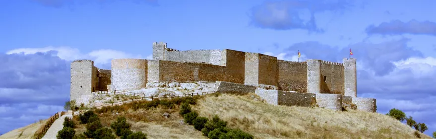Castillo de piedra sobre colina bajo cielo azul.