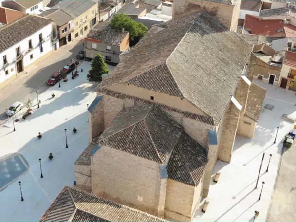 Vista aérea de una plaza urbana con iglesia de piedra y edificios tradicionales