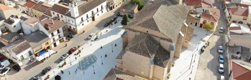 Vista aérea de una plaza urbana con iglesia de piedra y edificios tradicionales